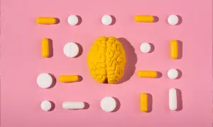 Żółty model mózgu otoczony białymi i żółtymi tabletkami i kapsułkami. Czy to symbol wsparcia dla serotoniny?