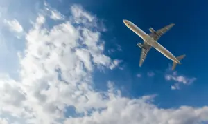 Samolot leci na tle błękitnego nieba z chmurami. Zastanawiasz się, ile się leci do Marsa Alam?