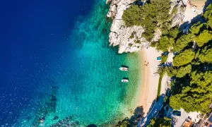Idealne miejsce na wakacje w Chorwacji: piaszczysta plaża, turkusowa woda i łodzie kołyszące się na falach.