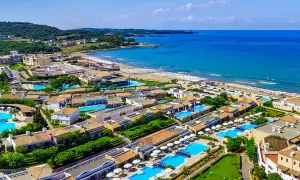 Idealne wakacje na Peloponezie: rozległy kompleks hotelowy z basenami i plażą nad turkusowym morzem.