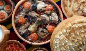 Bogactwo smaków kuchni bałkańskiej: pieczone mięso z ryżem, faszerowane cebule, chleb z ozdobami i ajvar.