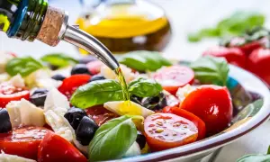 Sałatka caprese z pomidorów, mozzarelli, oliwek i bazylii, polana oliwą z oliwek. Idealna na zdrową dieta śródziemnomorska.