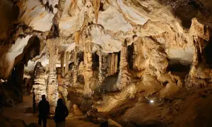 Dwie osoby zwiedzają imponujące jaskinie w Polsce, podziwiając stalaktyty i stalagmity.