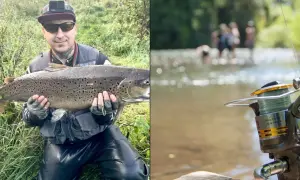 Wędkarz z dumą prezentuje imponującą rybę, być może płoć rekord polski. W tle widać rzekę i ludzi.