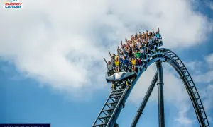 Ludzie krzyczą z radości na pokładzie Hyperiona, największego rollercoastera w Polsce, pędząc po stalowych torach na tle błękitnego nieba.