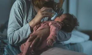 Mama karmi butelką noworodka, dbając o jego potrzeby. Mały brzuszek mieści niewielką ilość mleka, co odzwierciedla pojemność żołądka noworodka.