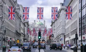 Londyn ozdobiony flagami Wielkiej Brytanii. Marzysz o wizie do Londynu? Ta ulica pełna taksówek i ludzi może być Twoim celem.