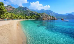 Piękna plaża z turkusową wodą i górami w tle. Idealne miejsce na wakacje, zastanawiasz się, ile się leci do Turcji?