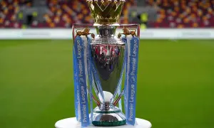 Trofeum Premier League, symbol mistrzostwa Anglii, lśni na tle zielonej murawy i trybun stadionu.