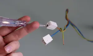 Hand prüft Kabel mit Schraubendreher, um eine Lampe anzuklemmen.