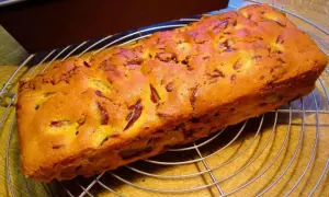 Frisch gebackener Pflaumenkuchen in Kastenform, goldbraun und mit saftigen Pflaumenstücken, kühlt auf einem Gitter ab.