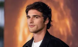Jacob Elordi, którego dziewczyna może być zazdrosna o jego urok, pozuje na tle ognistego krajobrazu.