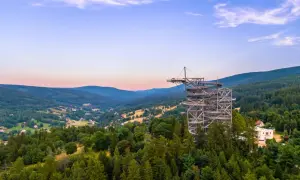 Metalowa konstrukcja sky walk wznosi się na znaczną wysokość nad zalesionymi wzgórzami, oferując zapierające dech w piersiach widoki.