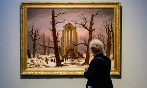 Besucherin betrachtet Caspar David Friedrichs "Abtei im Eichwald" in der Alten Nationalgalerie. Ein winterliches Motiv mit Ruinen und Kreuzen.