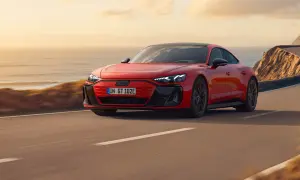 Czerwony Audi e-tron GT sunie po malowniczej nadmorskiej drodze o zachodzie słońca.