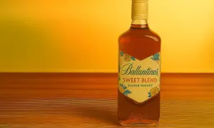 Butelka Ballantine's Sweet Blend na drewnianym blacie. Idealna do drinków, np. z colą lub jako baza do koktajli. Z czym pić Ballantines Brasil?