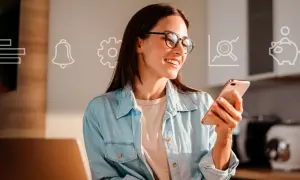 Uśmiechnięta kobieta w okularach trzyma smartfon, na tle ikony finansowe: wykres, dzwonek, koło zębate, lupa, skarbonka.