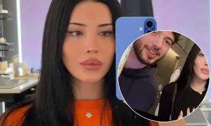 Kobieta z długimi czarnymi włosami, przypominająca czarodziejkę Liz, robi selfie. W tle widać mężczyznę.