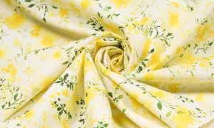 Ein zartes Popeline-Gewebe mit einem gelben Blumenmuster und grünen Blättern, das an einen sonnigen Frühlingsgarten erinnert.
