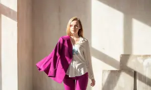 Kobieta w białej koszuli i fuksjowych spodniach, z marynarką w kolorze magenta zarzuconą na ramię. To właśnie magenta jaki to kolor!