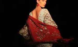 Mujer con traje de flamenca de lunares rojos y mantón bordado. Aprende como lavar un traje de flamenca para mantenerlo impecable.