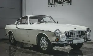 Vit Volvo P1800, en ikonisk bil som påminner om James Bond. Klassisk design med kromdetaljer och runda strålkastare.