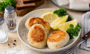 Filetti di merluzzo surgelati trasformati in gustose polpette, servite con spicchi di limone e prezzemolo. Perfette per ricette veloci e saporite.