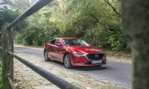 Czerwona Mazda 6 2.0 benzyna jedzie leśną drogą.