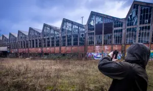 Exploration urbex à Angoulême : une silhouette capture l'architecture délabrée d'une usine abandonnée, ornée de graffitis.