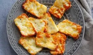 Gylla halloumi i airfryer, gyllene och krispiga bitar på en grå tallrik, kryddade med peppar.
