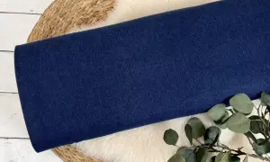 Dunkelblauer Denim-Stoff, aus dem Jeans gemacht sind, liegt auf einem Schaffell.