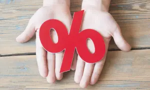 Dłonie trzymające czerwony symbol procentu. Dowiedz się, jak obliczyć odsetki ustawowe, aby zrozumieć finanse.