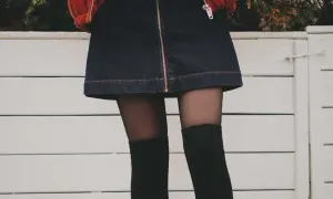Stylowy outfit z dżinsową spódniczką, czarnymi zakolanówkami i pomarańczową kurtką.