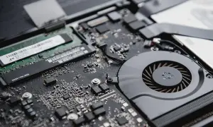 Detalle de la placa base de un portátil, mostrando un módulo de memoria RAM y el ventilador de refrigeración.