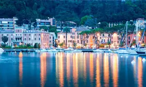 Serata a Toscolano Maderno: hotel illuminati, barche a vela e riflessi sull'acqua creano un'atmosfera magica.