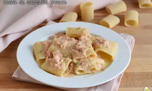 Piatto di paccheri conditi con un cremoso sugo di pasta al salmone fresco, guarnito con erba cipollina.
