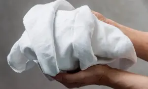 Hände halten ein zerknittertes, weißes Leinen. Es sieht aus, als würde es gleich gewaschen.