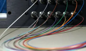Kolorowe włókna światłowodowe wychodzą z czarnego panelu. Ich kolejność jest widoczna na zdjęciu.