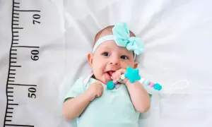 Bebé con diadema azul y mordedor, cerca de una cinta métrica que indica el percentil 15.