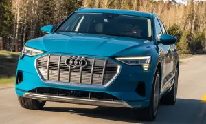 Blå Audi e-tron kör på en väg i skogen. En begagnad Audi e-tron som är perfekt för äventyr.