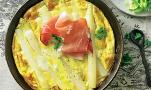 Spargel-Frittata mit Schinken in einer Pfanne, garniert mit Petersilie.