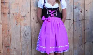 Dirndl mit pinkem Satinband-Schnürung und passender Schleife. Darunter ein karierter Unterrock.
