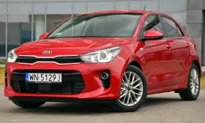 Czerwone Kia Rio przed budynkiem. Wymiana żarówki do jazdy dziennej w tym modelu jest prosta.