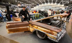 Man bredvid en rostig Oldsmobile 1955 med öppen dörr och motorhuv. Bilen har kromdetaljer och djupa fälgar.