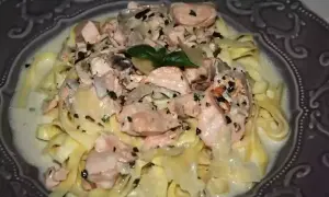 Tagliatelles onctueuses au saumon, parsemées d'herbes fraîches et de poivre noir, servies dans une assiette décorative. Un délice pour les yeux et les papilles.