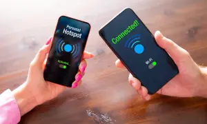 Dwie dłonie trzymają telefony. Na jednym ekranie "Personal Hotspot Activated...", na drugim "Connected! Wi-Fi". Pokazuje, jak udostępnić internet z telefonu.