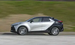 Srebrno-czarny Toyota C-HR 2019 w ruchu, z rozmytym tłem zieleni i drogi.