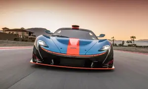 El McLaren P1, azul con franjas naranjas, acelera en una pista al atardecer, con palmeras y montañas de fondo.