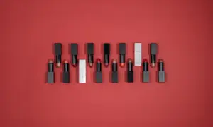 Une collection de rouges à lèvres aux teintes variées, dont un rouge rose éclatant, sur fond rouge.