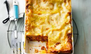 Eine frisch gebackene Lasagne in einer Auflaufform, mit einem Stück herausgeschnitten.